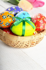 Rustic style painted easter eggs in basket on white table