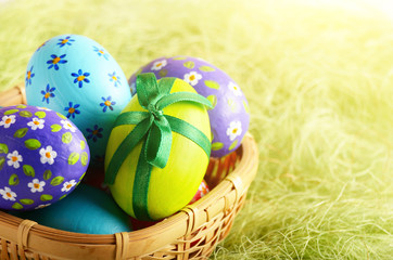 Rustic style painted easter eggs in basket on green background
