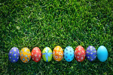 Easter eggs lying on green spring grass arranged in one lane. Space for text