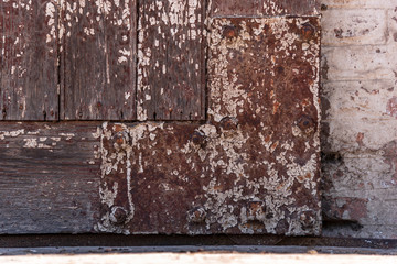 Iron rusted and unpainted angle of a wooden door with a bircks background