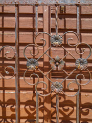 detail of an old wooden door and iron fence with flowers