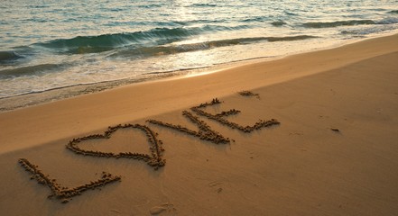 Valentines day concept, love heart shape handwriting on sand beach in sunrise and blue ocean.