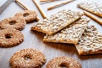 Crispy biscuit crackers with flax and sesame sunflower seeds on wooden background. Daylight, selective focus. The concept of healthy eating.