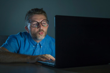 lascivious aroused porn addict man in nerd glasses watching sex movie online late night at laptop...