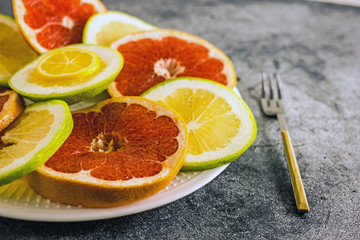 Rings of grapefruit and pomelo on a plate of different colors, next to a fork. Background with citrus. Background with grapefruit