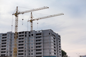 Fototapeta na wymiar Two cranes build multi-storey house