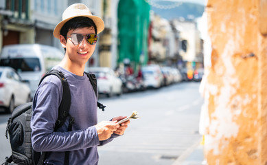 A blogger tourists from Southeast Asia Visit Phuket in Thailand are Captured in the old town during write travel reviews with sunlight and temple background in travel concept.