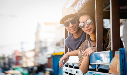 A couple of blogger tourists from Southeast Asia. Visit Phuket in Thailand are selfies on local bus. Captured in the old town of Phuket during write travel reviews with sunlight in travel concept .