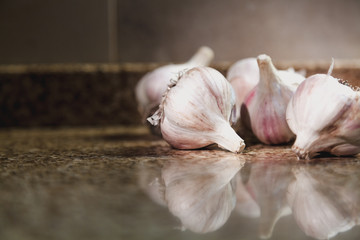 Several heads of garlic lie on a granite table