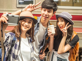 travel concept.couple of love reading book wating train.Asian beautiful girl wearing hat holding coffee cup and smart man holding 