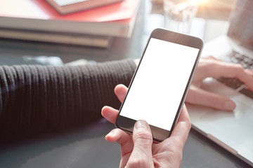 Closeup view woman hands using mobile smartphone and laptop. Space mockup for design layout. Loft interior sunlight.