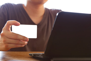 man holding credit card and using laptop computer