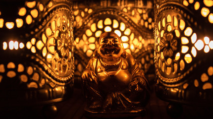 Obraz premium Złota figura mnicha z ciepłym światłem świec.