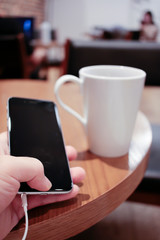 listening to music on a smartphone while drinking coffee alone in a cafe