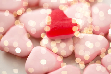 valentines day, sweets and confectionery concept - close up of red and pink heart shaped candies over festive lights