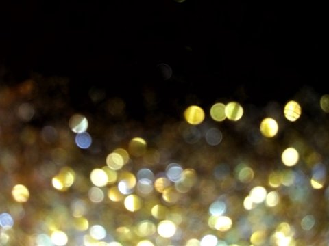 glittering blurred golden yellow round lights on a black background with area for copy space or text