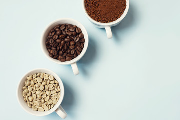 Different types of coffee - ground, grain and unroasted on blue pastel background