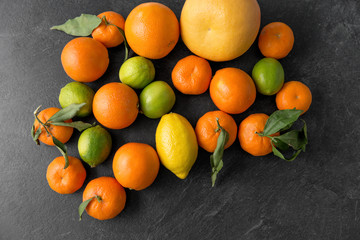 food, healthy eating and vegetarian concept - close up of citrus fruits on stone table