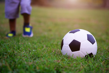 Asian kid playing soccer or football in the park