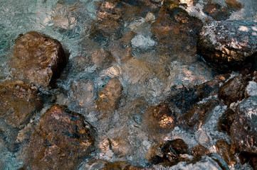 Beautiful multi-colored stones playing colors in a raging stream of river water. Abstract modern and stylish background for design or print