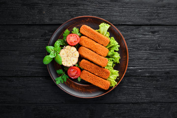 Baked Fish Sticks. On a black background. Top view. Free copy space.