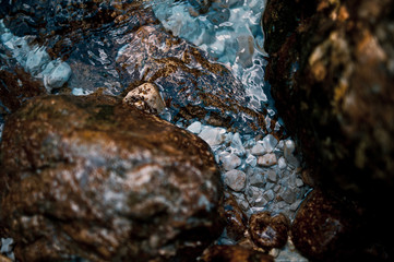 Beautiful multi-colored stones playing colors in a raging stream of river water. Abstract modern and stylish background for design or print