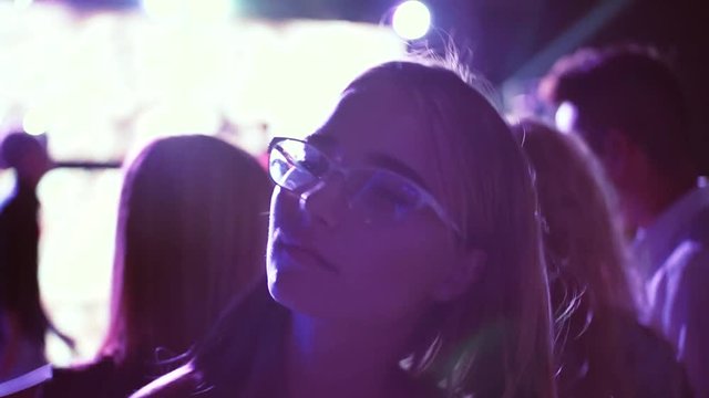 Fashionable young woman with glasss dance at nightclub music and disco lights in the background of the party attractive trip travel portrait close up slow motion