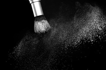 white powder splash and brush for makeup artist or beauty blogger in black background