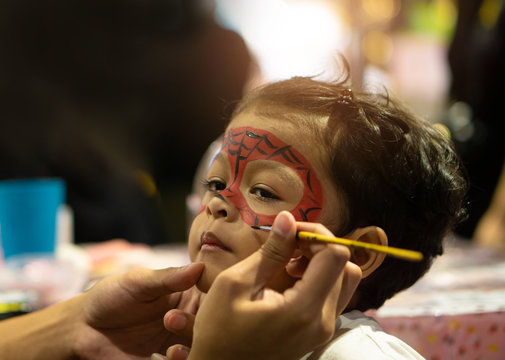 Asian kid boy with painted face as a spider
