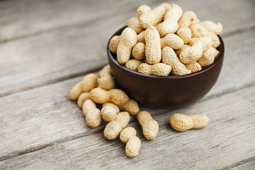 Peanuts in the shell, in a wooden cup on the table.