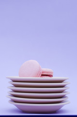 Two macaroons on a stack of beige saucers.