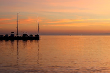 Boats in a harbor at sunset with beautiful colorful sky.