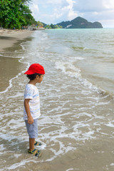 Asian boy playing on the thailand sea and white sand beach