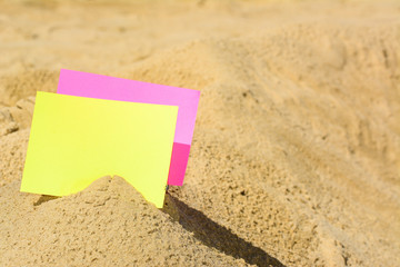 A blank yellow and red card buried in sand at the beach