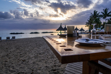 Fototapeta premium Sonnenuntergang am Strand mit einem gedeckten Tisch im Vordergrund