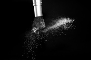 white powder splash and brush for makeup artist or beauty blogger in black background