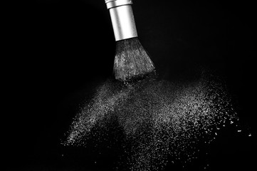 white powder splash and brush for makeup artist or beauty blogger in black background