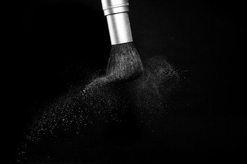 white powder splash and brush for makeup artist or beauty blogger in black background