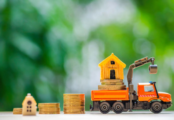 Obraz na płótnie Canvas House or Home model on near of coins stack with home key on hand. Concept for loan, property ladder, financial, mortgage, real estate investment, taxes and bonus.