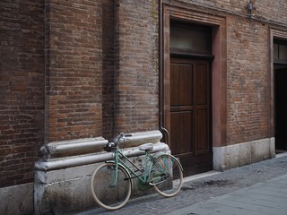 Fototapeta na wymiar Ferrara, Italy. Bicycle resting on the facade of a building.