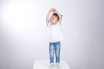 Curious little girl is standing on a white background and posing.