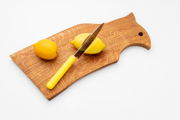 Fresh lemons a cutting board.A half of a yellow lemon on a wooden chopping board with a knife.Composition of delicious citrus fruit.Fresh mojito drinks with lime, lemon.Copy space.Sliced and whole