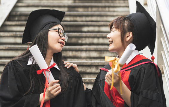 Portrait of two Asian students in bachelor robes on her graduation day University. education, graduation and people concept. They are very happy about this.