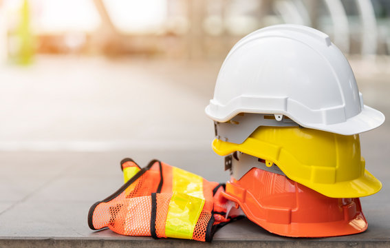 safety first project of workman as engineer or worker or crew and insurance, business concept. construction safety gear including a white, yellow and blue hard safety helmet on concrete floor on city