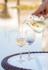 White Portuguee wine poured to glasses on an outdoor table by the river in Tavira, Portugal.
