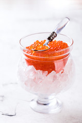Salmon and trout red caviar in a glass jar on a light marble background. Seafood  Healthy Food Concept. Snack.Copy space for Text