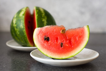 A piece - a portion of ripe juicy watermelon on a platter on the background of the whole.