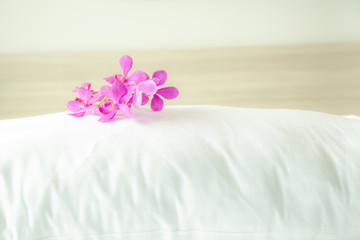 Pillows and beautiful orchid flower on top in the bed room.