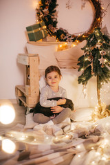 Beautiful baby girl near a Christmas tree with gifts with little boy feeding black vietnamese piglet. Concept of the Chinese New Year 2019 of the Pig