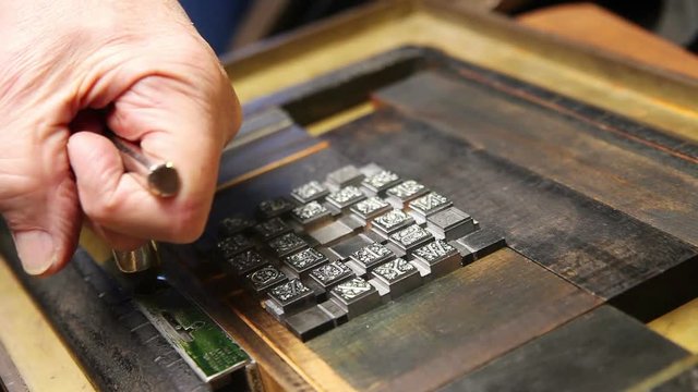 A printer tightens a block of type with a quoin key